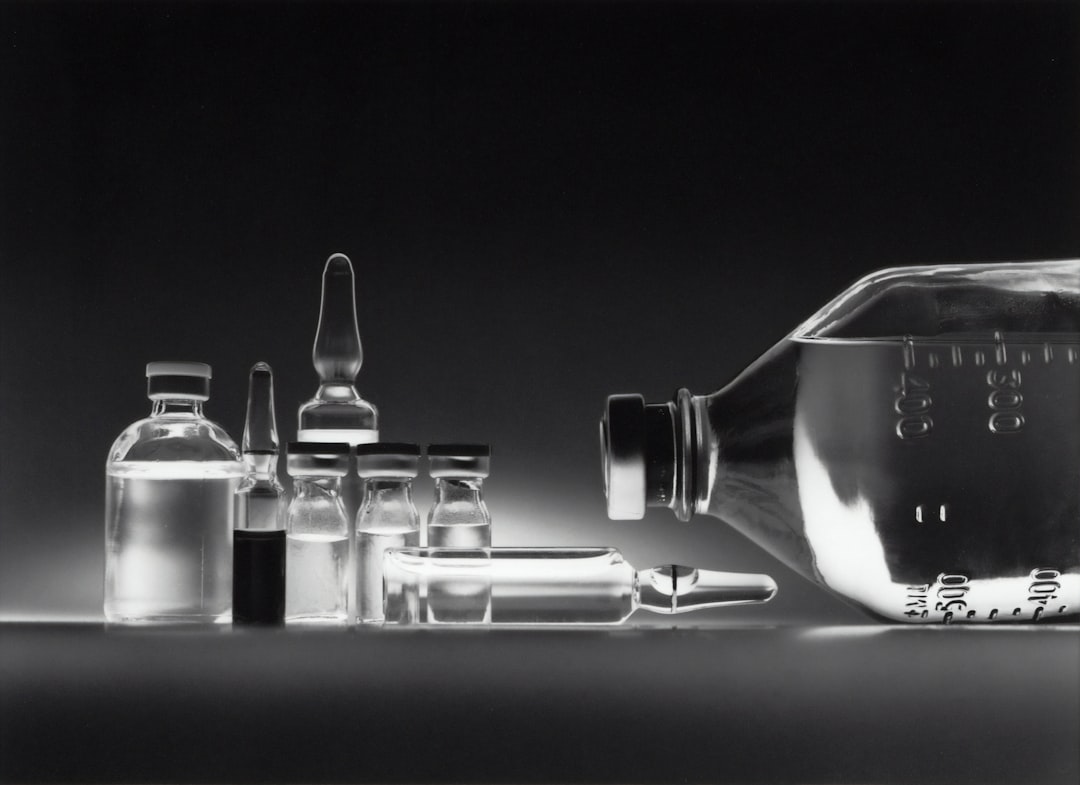 A collection of glass vials and a larger bottle on a dark background.